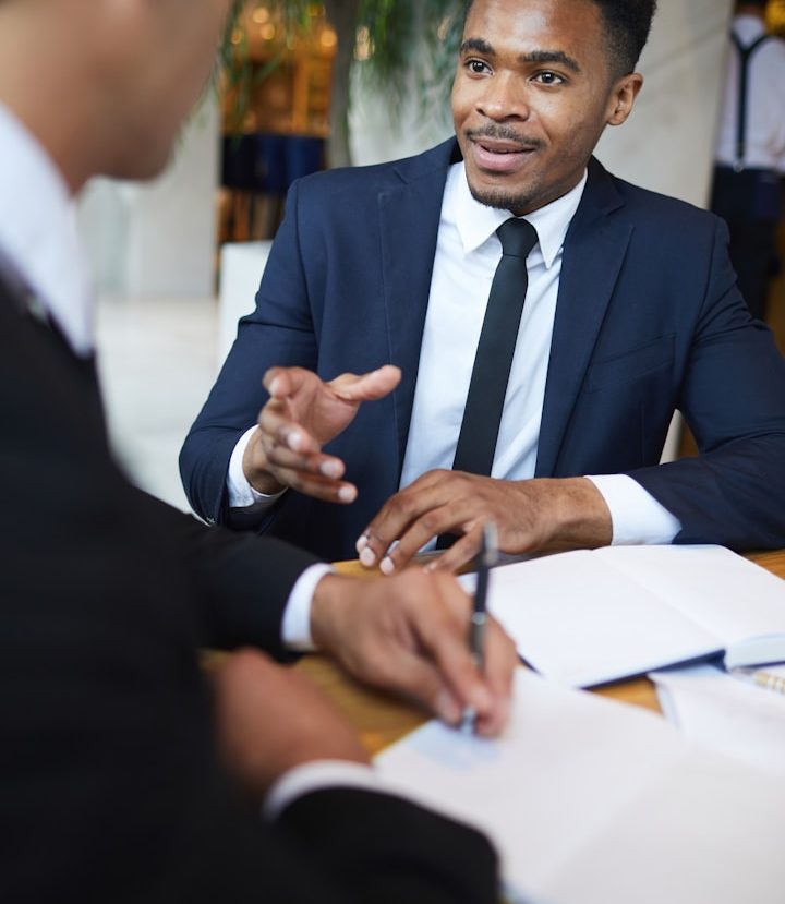 Stock photo of two business men. Two men in business attire discussing over papers at a table.